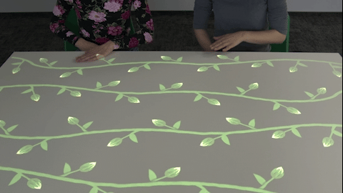 Senior activation table — older adults playing an interactive game projected on a tabletop